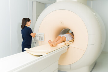 Young woman at the MRI machine getting a brain resonance - obrazy, fototapety, plakaty
