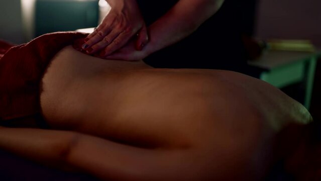 classical massage in spa salon or medical clinic, masseuse woman is stroking back of female client