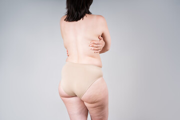 Overweight woman's body with fat hips and buttocks, obesity female back on gray background