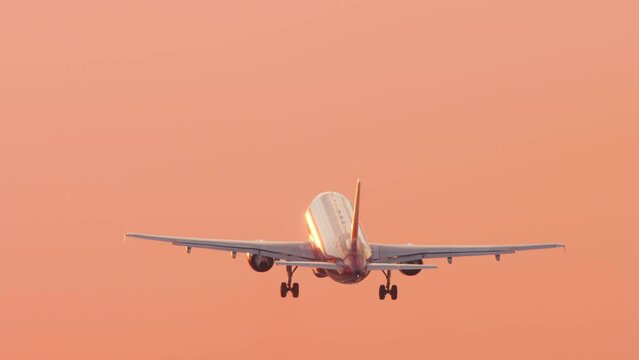 Jet airplane takeoff and climbing into the sunset. Picturesque sunset and flying away airliner. Tourism and travel concept, modern aviation