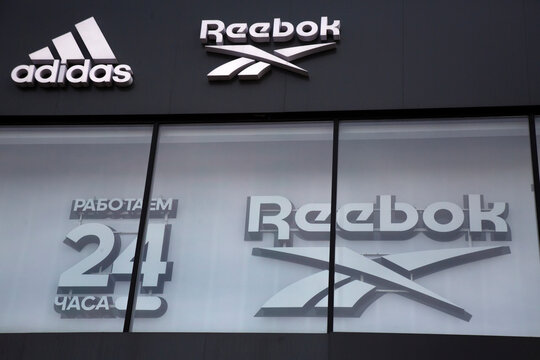 Signs of the Reebok and Adidas trademarks on a facade of a shopping complex on Novy Arbat Street in the center of Moscow. The Russian words reads "Works 24 hours"