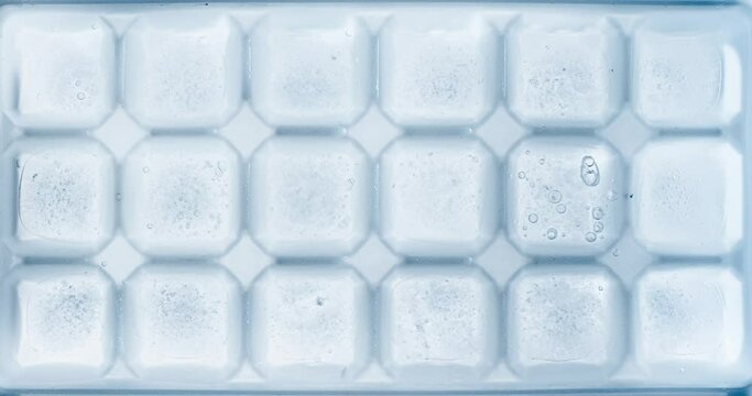 Timelapse of water freezing ice cubes in an ice tray.