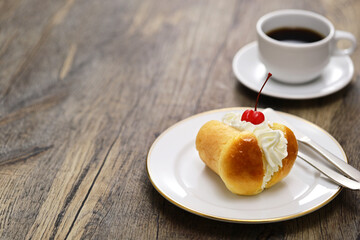 rum baba ( baba au rhum ) decorated with whipped cream ; traditional French and Italian dessert and a cup of coffee - obrazy, fototapety, plakaty