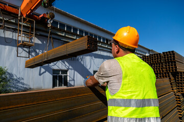 Worker transporting stack of metal pipes with gantry crane