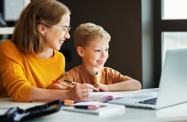 Fototapeta na wymiar Cheerful mother doing homework with son at home