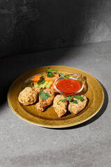 American appetizers buffalo wings with vegetables and sauce on gray stone table. Beer appetizer - Bbq wings on concrete background with hard shadow. Dark menu for pub. Chicken wings. Junk food.