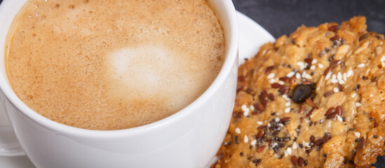 Cup of coffee with milk and fresh baked oatmeal cookies with honey and healthy seeds. Delicious crunchy dessert