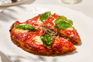 Traditional italian dish - milanese steak in breaded and parmesan on white ceramic plate. Milanese beef with tomato sauce and basil. Italian beef steak alla schnitzel with bone. Italian chop beef.