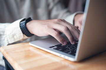 Man working at home, typing and searching data on laptop computer on office table. Freelancer at work. Casual business, online job, telecommuting concept