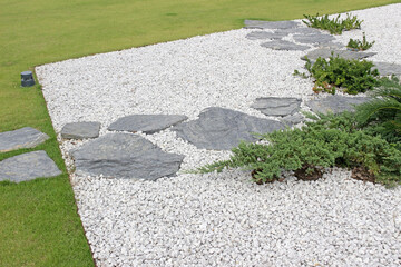 Garden details: A graveled area with flat slate slabs forming paths and occasional ground spreading...