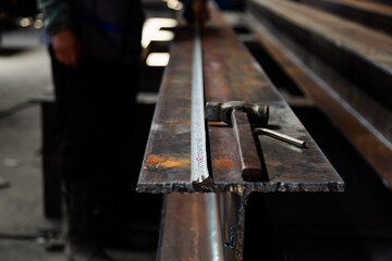 Hammer and measuring tape laying on steel in warehouse