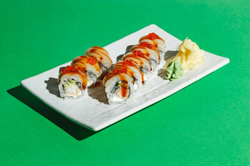 Sushi rolls with eel, shrimp, cucumber and cream cheese, decorated with red caviar. Hard light, deep shadow