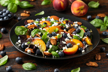 Peach, blueberry salad with vegetables, feta cheese and pecan nuts. Healthy summer food
