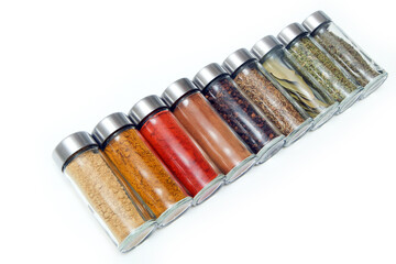The different types of spices and herbs stored inside the small closable glass bottle isolated on a white background. 