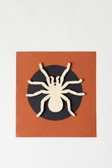 wood spider shape on paper with black circle and brown square