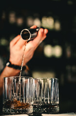 Bartender pouring whiskey on glass in bar