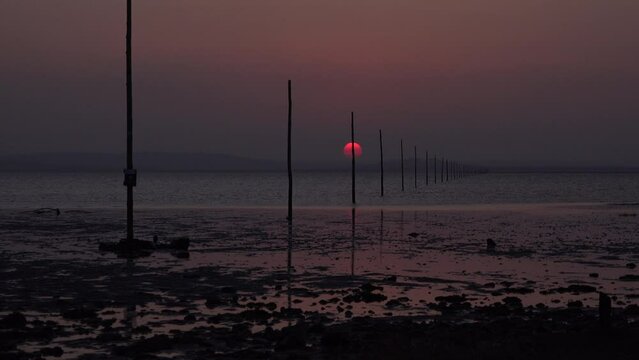 Sunset over sand on Lindisfarne holy island relaxing and meditation in nature. Northumberland seaside with sun going down over water in evening UK 4K