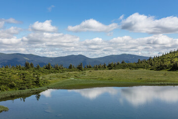 Fototapeta na wymiar The water surface of a blue lake against the background of the Gorgan mountain range, Carpathians