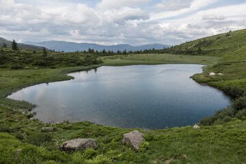 The bowl of a mountain lake surrounded by forests and peaks