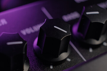 Volume knob on its full setting on a guitar amplifier. Audio amplifier under purple stage lights....