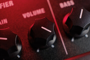 Guitar amplifier knobs - audio amplifier potentiometers, volume knob on full power, bathed in red...