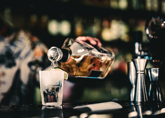 Bartender pouring tequila strong alcoholic drink into small glass