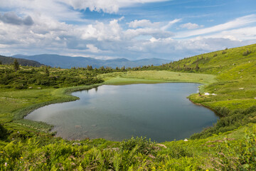 Fototapeta premium The bowl of a mountain lake surrounded by forests and peaks