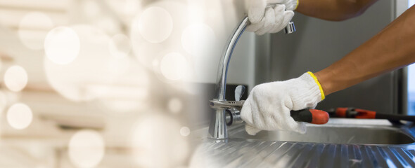 Plumber fixing white sink pipe with adjustable wrench.