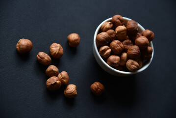 Delicious hazelnuts in a ceramic bowl on a black background. Delicious breakfast of nuts.