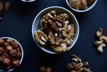 Delicious walnuts in a ceramic bowl on a black background. A delicious breakfast of Juglans regia nuts.