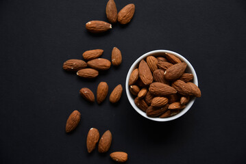 Delicious almonds in a ceramic bowl on a black background. Delicious breakfast of almonds.