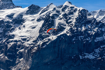 Single paraglider with the snow covered Swiss alps in the background. 