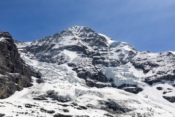 Fototapeta na wymiar Side of the Jungfrau mountain in the Bernese Oberland in Switzerland. Large pieces of of glacial ice can be seen on the side of the mountain. 