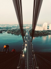 Two roofers are approaching the bridge in Ukraine on the long wires
