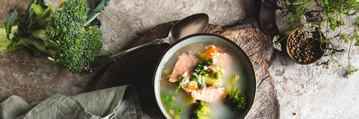 bowl with traditional finnish soup with salmon, broccoli and green peas on the table