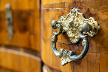 Decorative metal drawer handle in an antique desk with inlaid wood, Mid-18th century, close up.