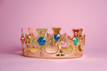 Isolated gold crown with jewels isolated on pink background