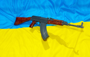 The old assault rifle above the Ukrainian flag symbolizes resistance against the aggressor