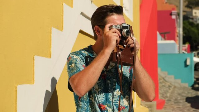Young man photographer takes photographs with camera in a city. Travel, vacations, professional freelance work and active lifestyle concept. stylish man with a film camera takes a photo