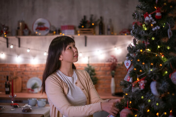 a pretty dark-haired Korean girl in a cozy Christmas room with festive bokeh lights in the evening...