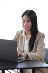 Attractive beautiful Asian business woman working on laptop on desk in office.