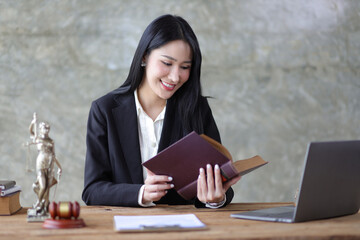 Charming young woman lawyer is reading a law book and working at a desk in a law firm.