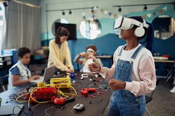 Portrait of young black girl using VR technology in engineering class, copy space
