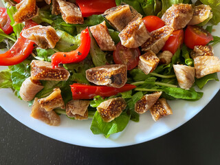 Delicious fig and arugula salad on white plate, top view. 
