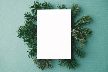 Christmas card mock up. Modern greeting card flat lay with green fir branches on green background. Empty postcard template with space for text. Merry Christmas and Happy Holidays!