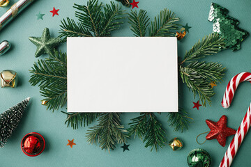 Fototapeta na wymiar Christmas card mock up. Modern greeting card flat lay with stylish christmas decorations and fir branches on green background. Empty postcard template with space for text. Merry Christmas!