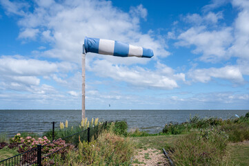 Windsock in the Netherlands. A windsock (also called a wind cone) is a conical textile tube that resembles a giant sock. It can be used as a basic indicator of wind speed and direction