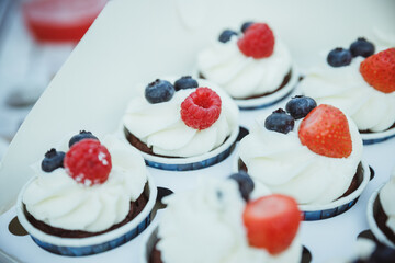 Delicious mini tarts.Mini Pavlova meringue with whipped cream and blueberries and strawberries, top view.Healthy dessert breakfast, snack, morning table.