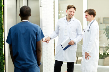 Obraz premium Group of cheerful doctors waiting for elevator in modern hospital building