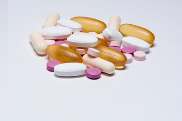 Closeup of a stack of pills, tablets and capsules on white background with copy space on bottom.